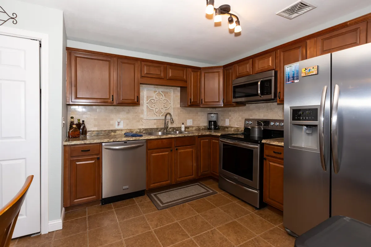 A warmly lit kitchen featuring cabinets, a spacious countertop, modern appliances, and a sink. The setting is inviting and functional, ideal for preparing meals and gathering with friends or family. Small decor accents suggest thoughtful touches throughout the space.