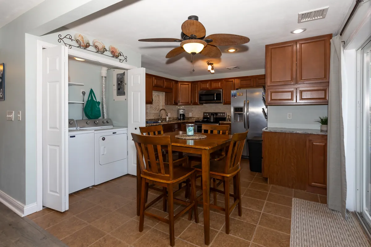 A cozy, open kitchen and dining area with modern appliances, a large table, and an adjacent laundry space. Designed for convenience and casual gatherings, the setting feels welcoming for cooking together or enjoying a quick breakfast before a day of adventure.