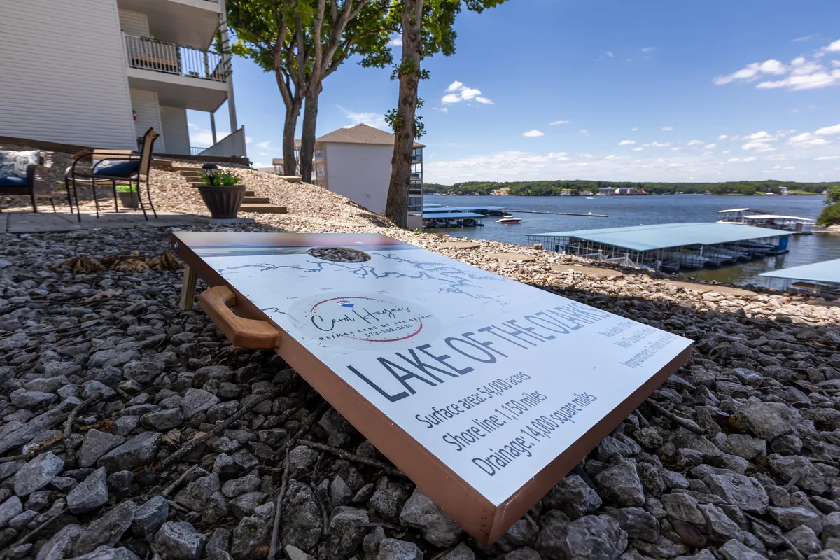 This exterior view highlights the beautiful lake, an informational sign, and landscaped features. The scene evokes the sense of outdoor activities like walking, boating, or simply relaxing by the water, with open space perfect for exploring with pets.