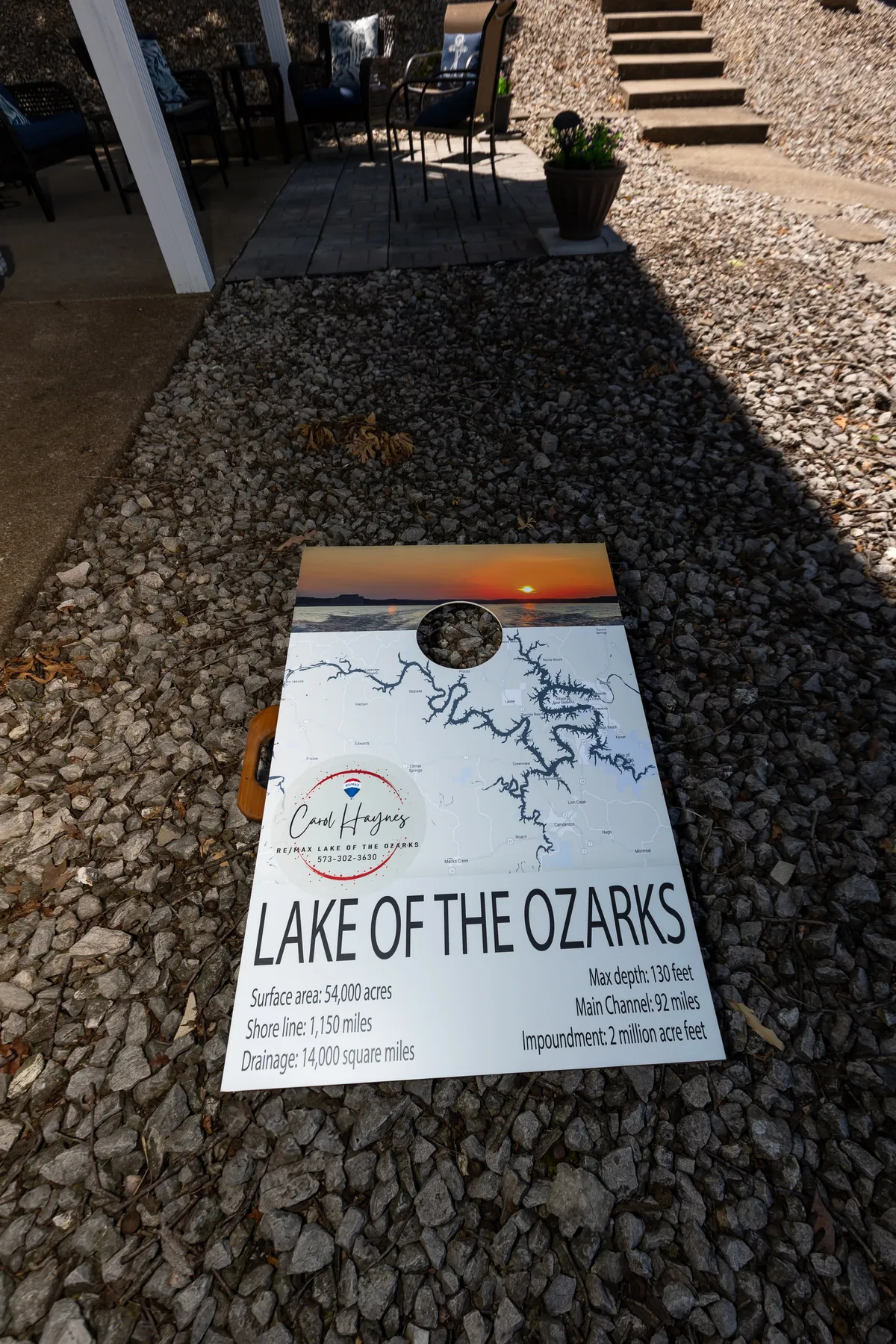 A landscaped patio area with an informational board about Lake of the Ozarks, offering cushioned outdoor seating that invites relaxation. The setting is casual and relaxed, suggesting a perfect spot for enjoying drinks or socializing while taking in the views.